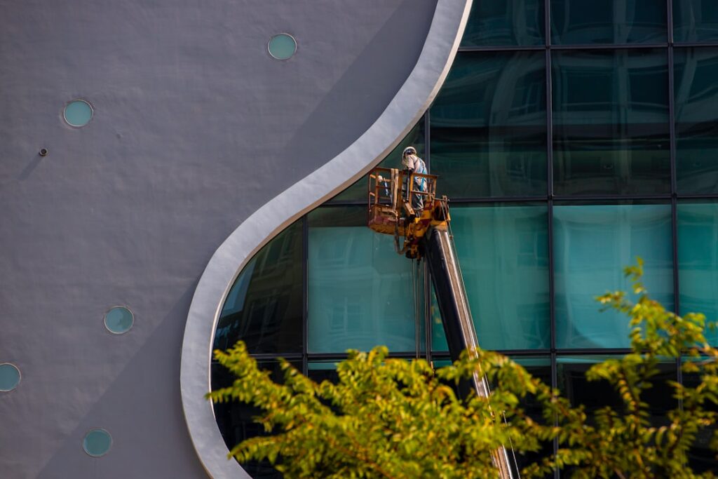Professional architect or contractor wearing a hard hat stands on a bright construction site, reviewing digital blueprints...
