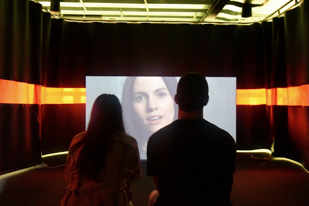 Professional in a minimalist, modern office environment interacting with a floating holographic user interface, representi...