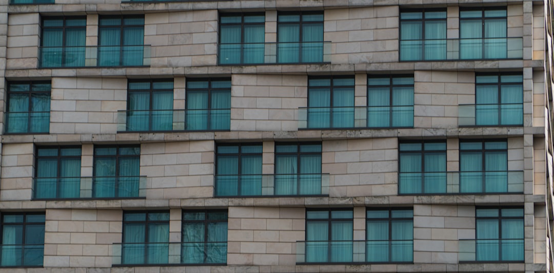 A professional realtor or contractor stands in front of a modern building, using a tablet to track business results and client data on-site.