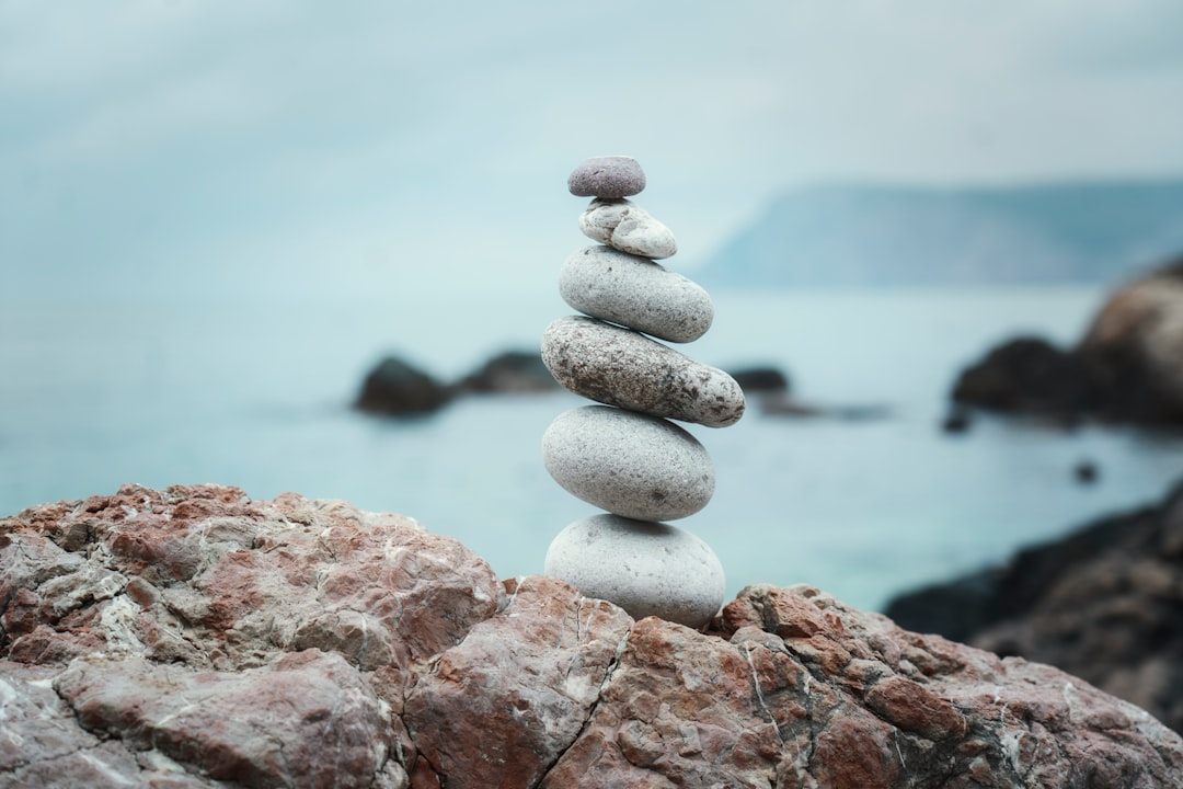 A stack of perfectly balanced stones sitting on a clean, modern desk next to a laptop, symbolizing stability, focus, and calm amidst technological change.