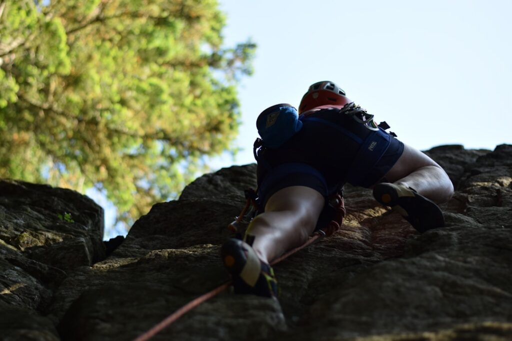 Two professional rock climbers collaborating to ascend a sunny mountain face, representing the trust and partnership of a ...