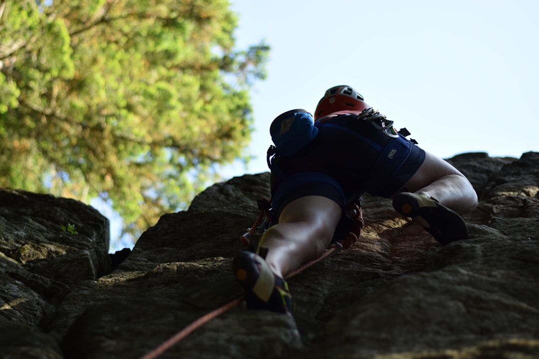 Two professional rock climbers collaborating to ascend a sunny mountain face, representing the trust and partnership of a long-term client relationship.