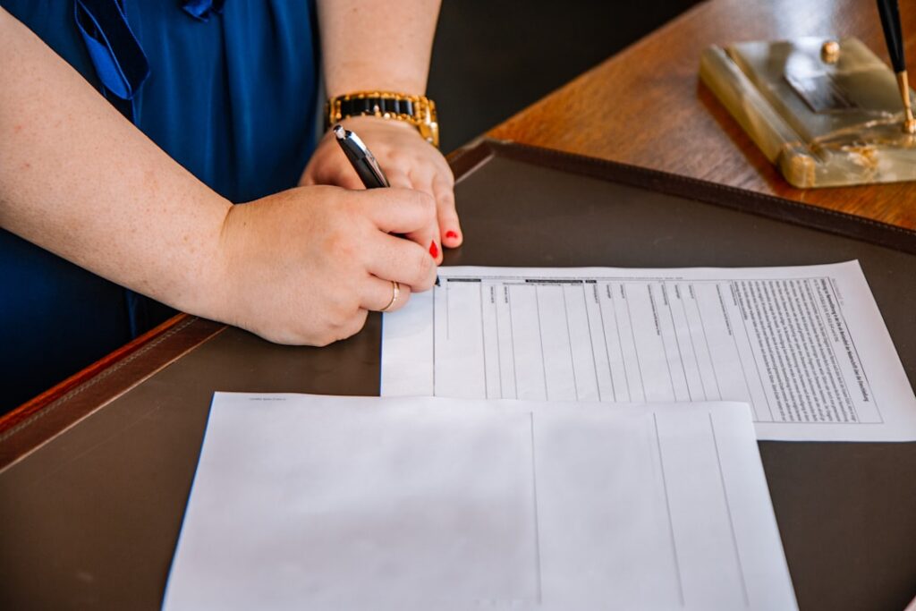 Close-up of a person's hands decisively tearing a formal business contract in half in a modern office, symbolizing breakin...