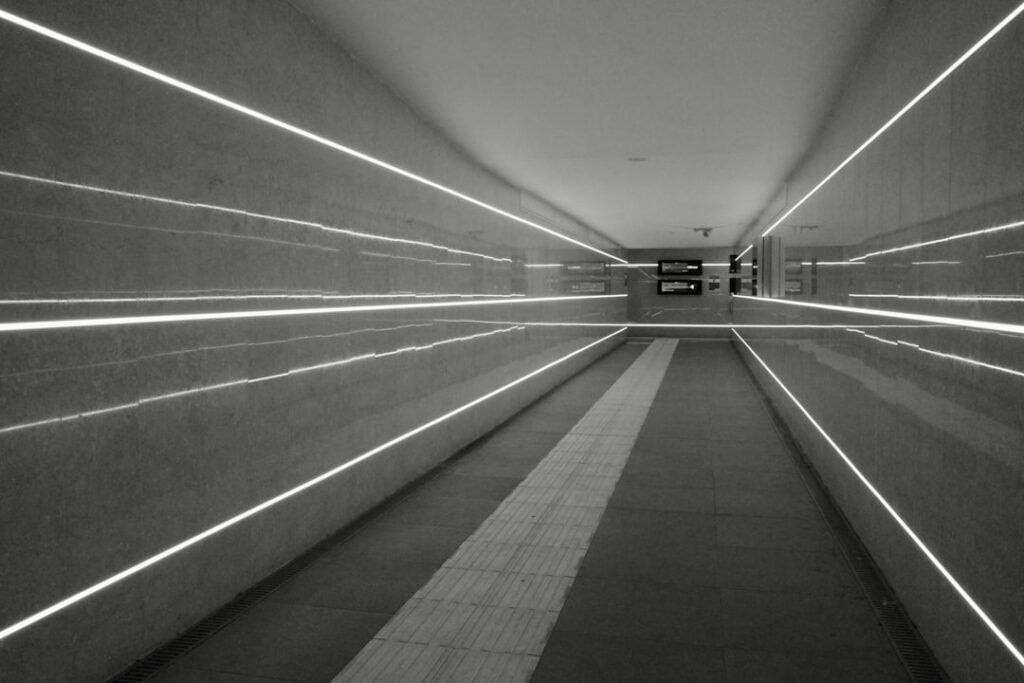 Person stands at the entrance of a brightly lit, modern maze, symbolizing a clear path through the complex challenge of AI...